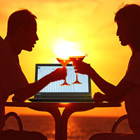 Couple at romantic dinner with laptop on table.